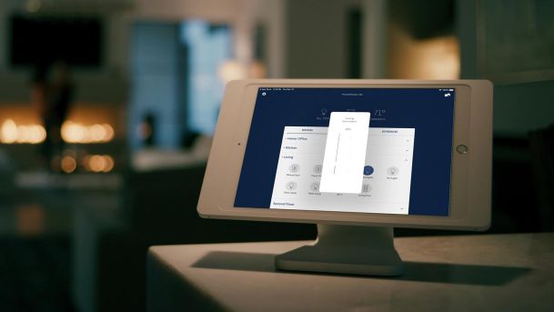 Lutron App on an iPad. Behind a couple dancing near a fireplace blurred.