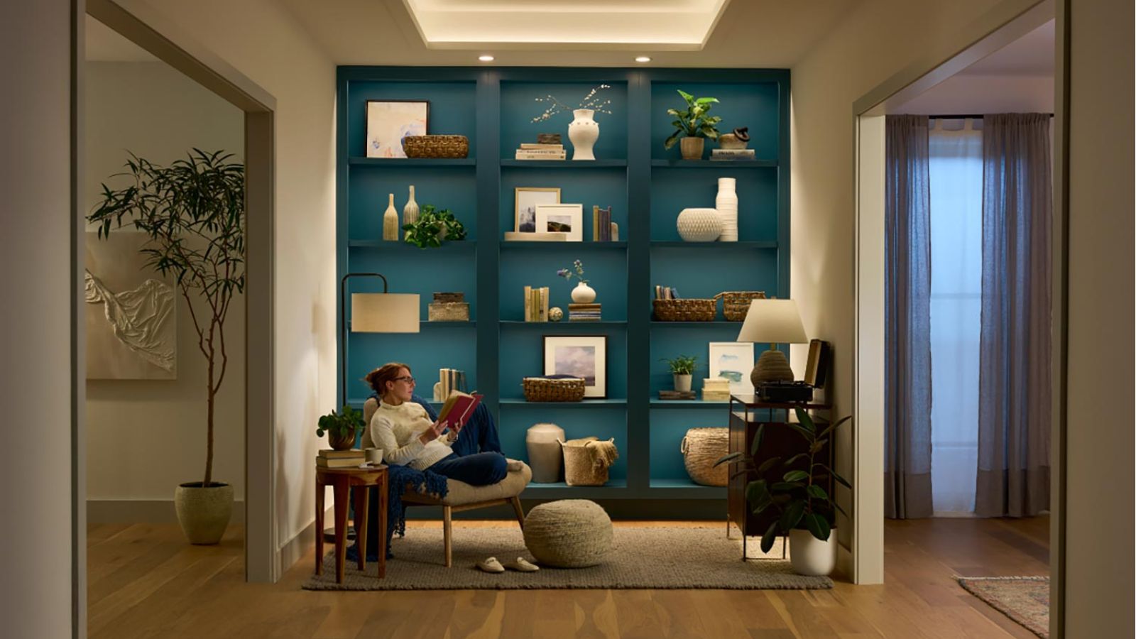 Cozy reading nook with teal built in shelves, warm lighting, and decorative items